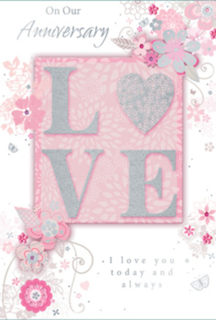 The photograph captures an anniversary card whose delicate detailing suggests the same thoughtful artistry you might expect from Morden Florist when creating a bespoke bouquet. At the heart of the design is the word "LOVE," spelled out in large, raised letters that stand proud from the card's surface. These letters are coloured in a soft, powder-pink hue and gently coated with fine glitter, producing a quiet shimmer when the light touches them. A slim outline of silver encircles each character, adding clarity and a hint of sophistication, reminiscent of a wedding ring's gleam. The embossing creates subtle shadows and makes the word feel almost three-dimensional, as though it could be picked up off the card. The background is a serene wash of blush pink, evoking the gentle warmth of late afternoon light drifting over Morden Hall Park. Flowing from around the central word, a series of beautifully stylised flowers and leaves sweep across the card, drawn with slender, graceful lines. The blossoms themselves are rendered in muted whites and soft greys, with delicate silver highlights that lend a faint sparkle similar to morning frost on garden petals. Their shapes are suggestive rather than literal, calling to mind the blend of roses, small filler flowers, and trailing greenery often used in romantic anniversary arrangements delivered in Morden. The vines and flourishes curl naturally around the letters, cradling the word "LOVE" in a loose, organic frame, much like foliage encircling the central blooms in a bouquet. The overall lighting is gentle and balanced, revealing both the texture of the raised lettering and the subtle variations in colour. Inside, an elegant script message offers warm anniversary wishes, the flowing handwriting echoing the curves of the illustrated vines. This card feels like a paper expression of enduring love, ideal to accompany flowers delivered across Morden, from cosy terraces near the high street to peaceful homes tucked away beside Morden Park.